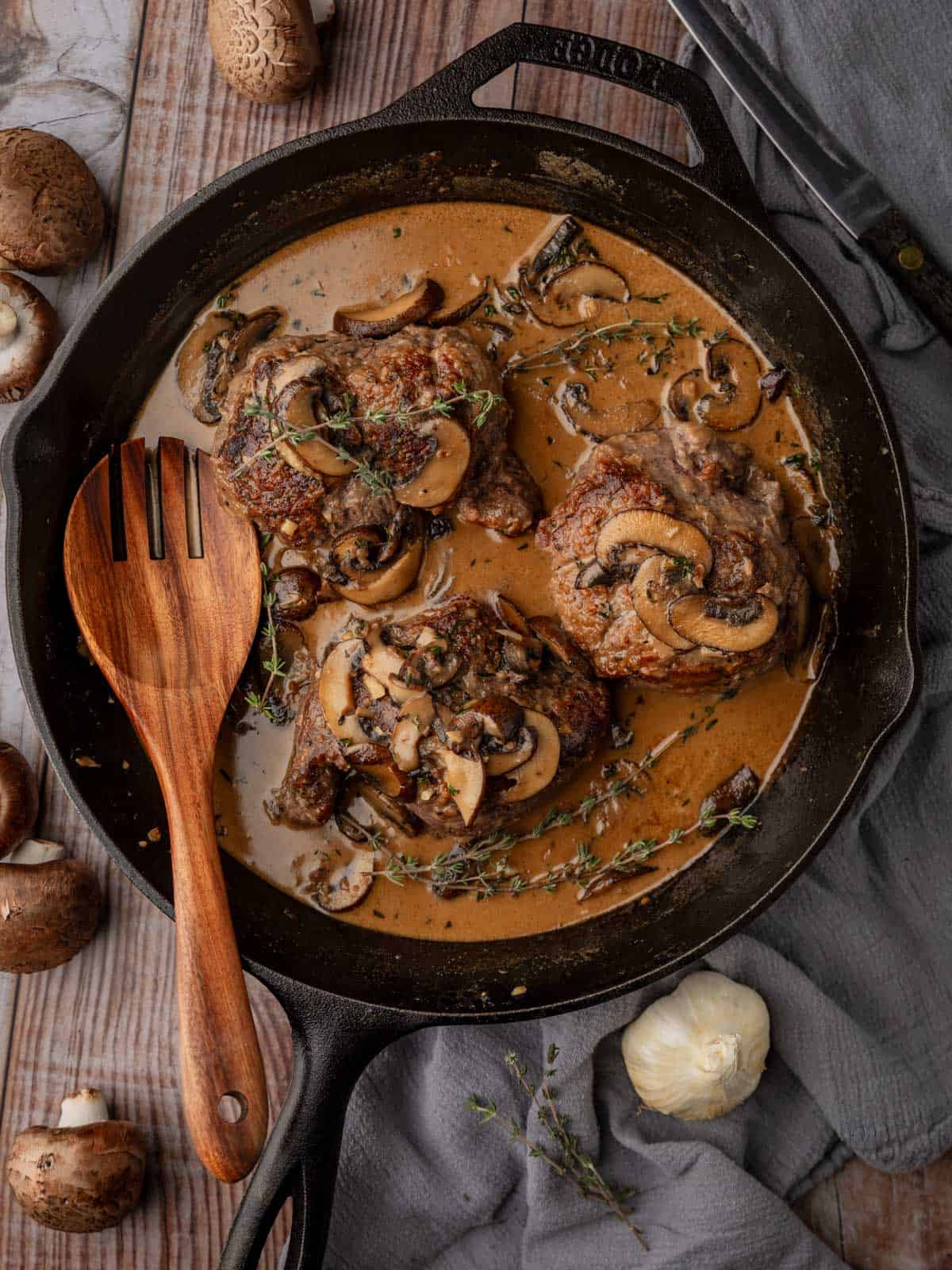 steak with marsala mushroom sauce in a cast iron skillet with fresh thyme sprigs.