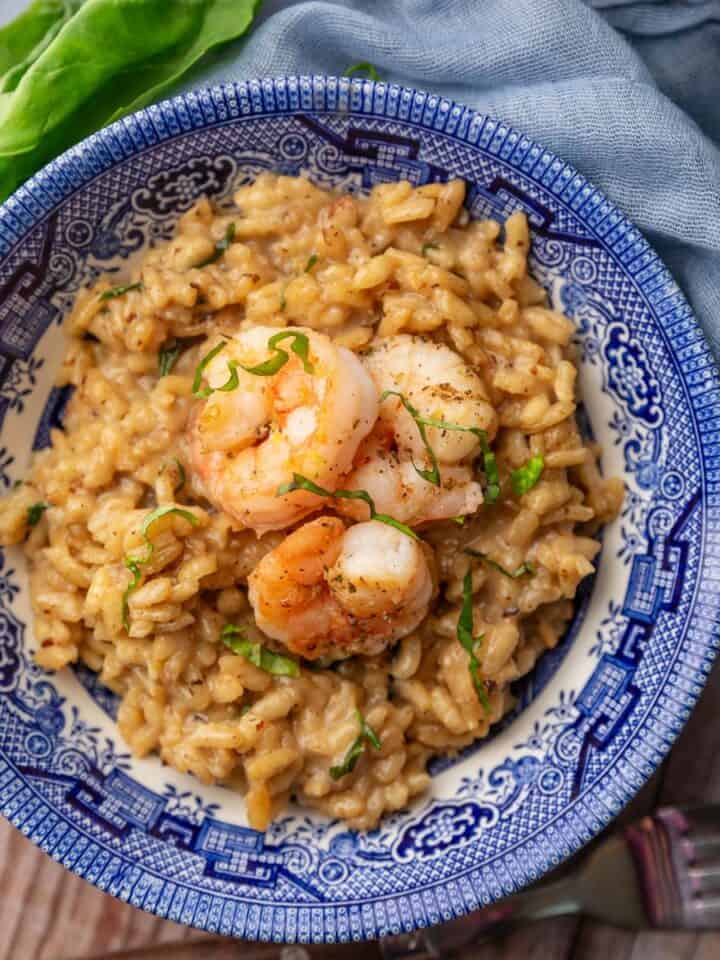 blue and white bowl filled with risotto with shrimp on top.