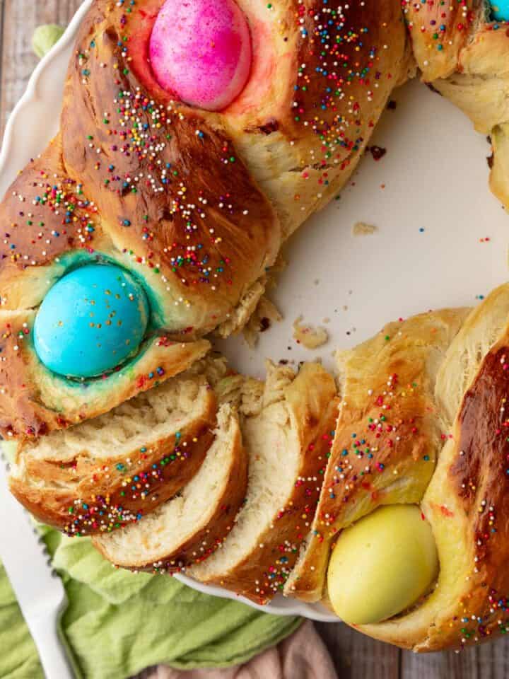 partially cut braided italian easter bread with colored eggs in it.