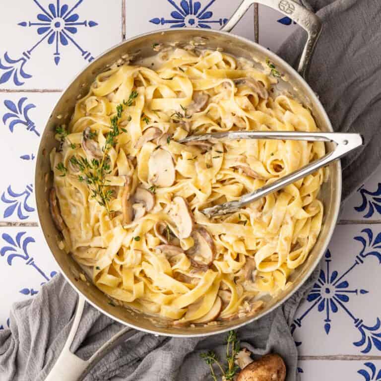 pan of tagliatelle pasta in a creamy mushrooms sauce with fresh thyme on top.