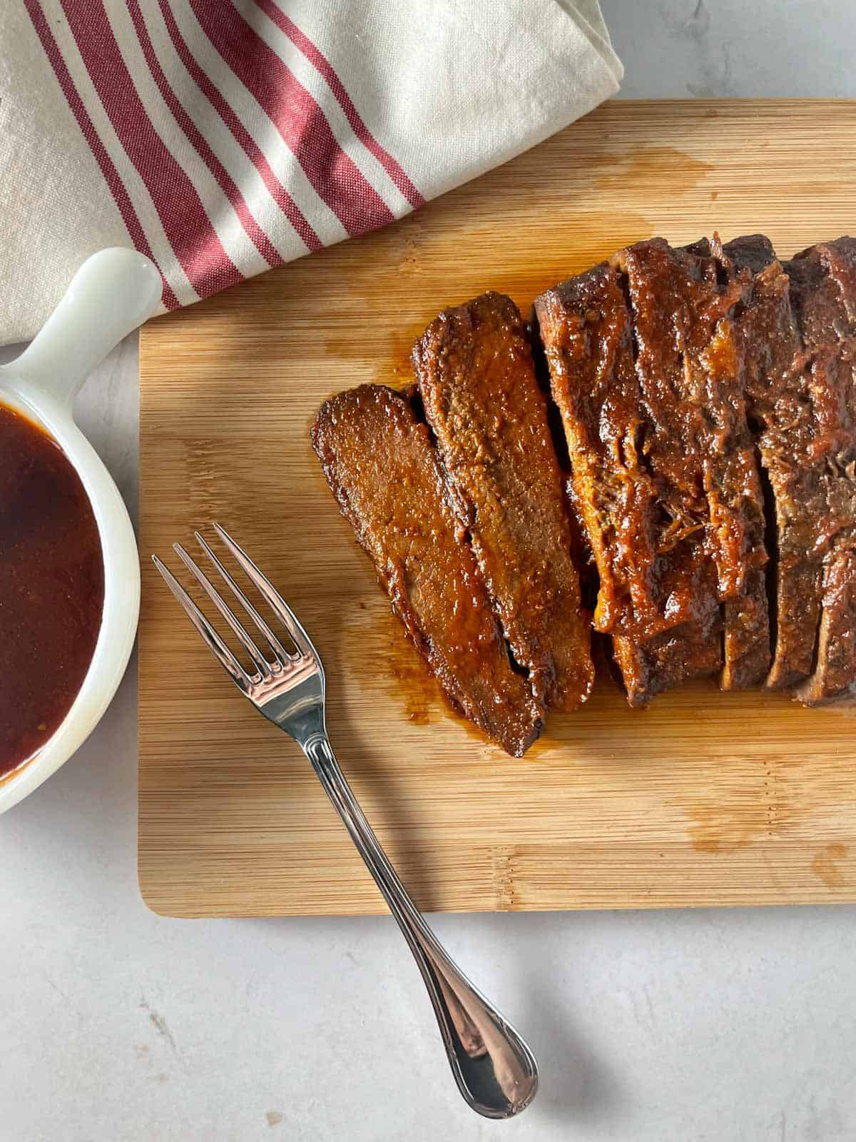 sliced bbq beef brisket on a cutting board with a fork.