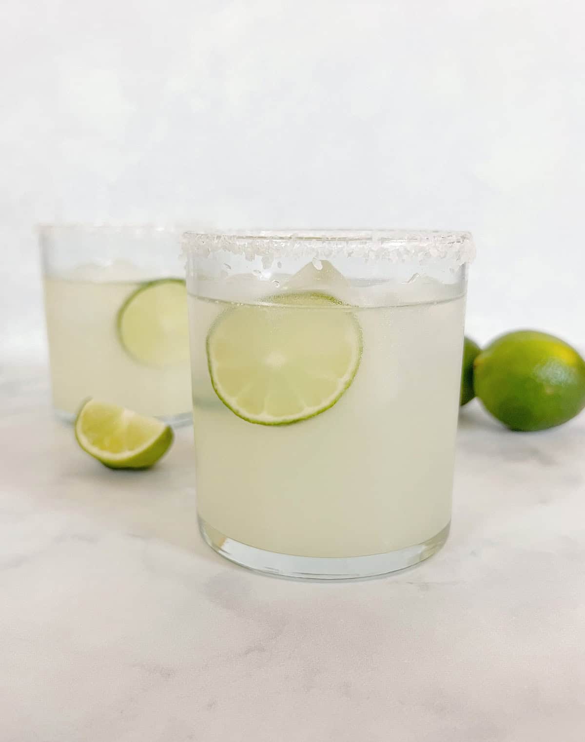 limemade margaritas in clear glasses garnished with fresh lime slices.