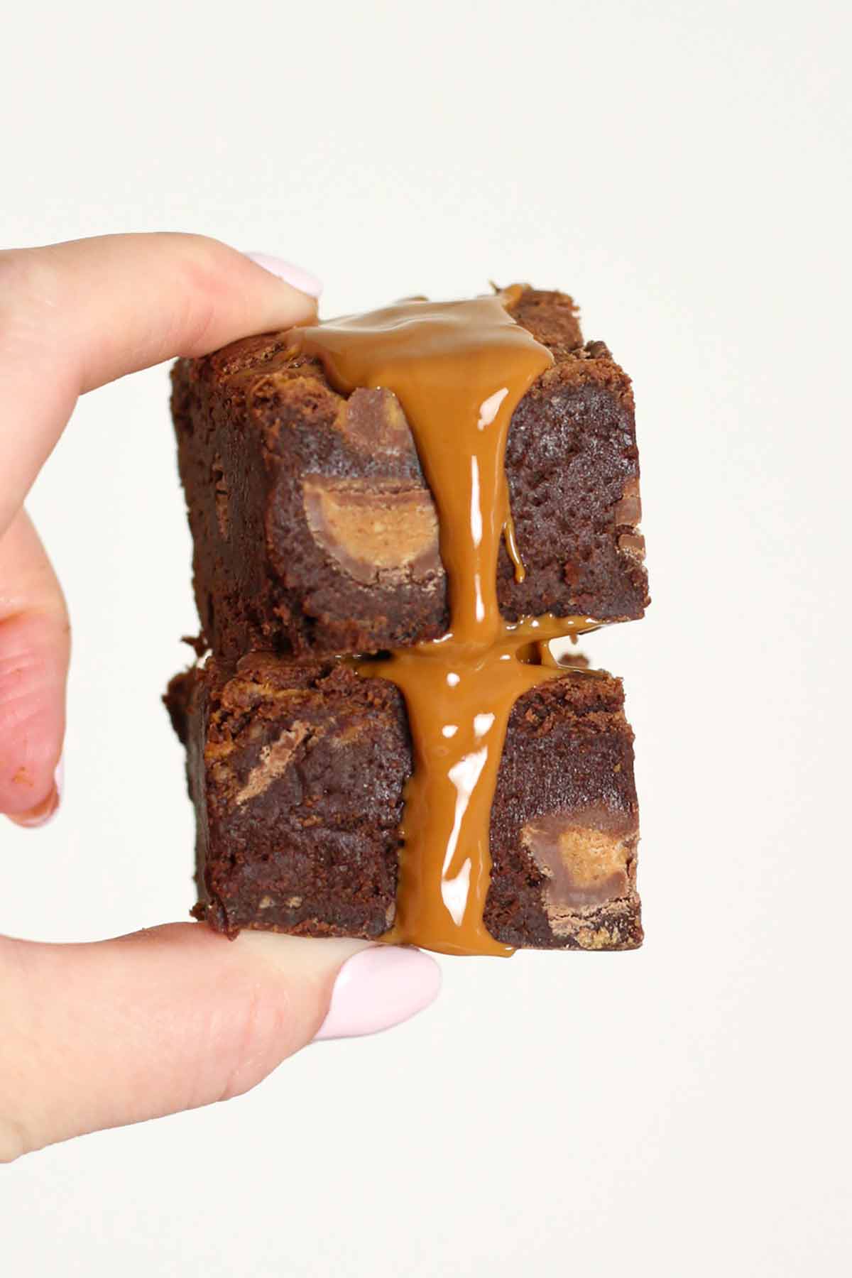 hand holding two peanut butter brownies dripping with chocolate.