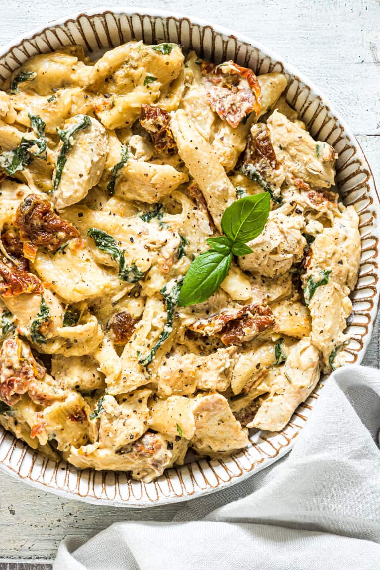 tuscan chicken pasta topped with fresh basil.