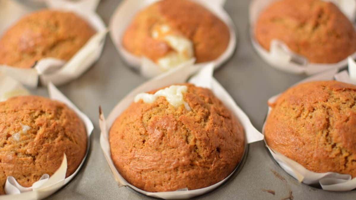 carrot cake and cream cheese stuffed muffins in a tin.