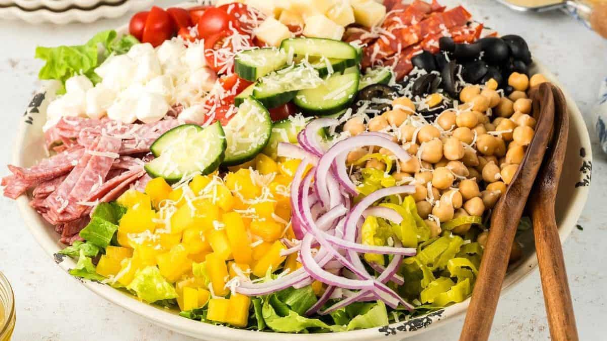 italian chopped salad with a bowl with wooden serving utensils.