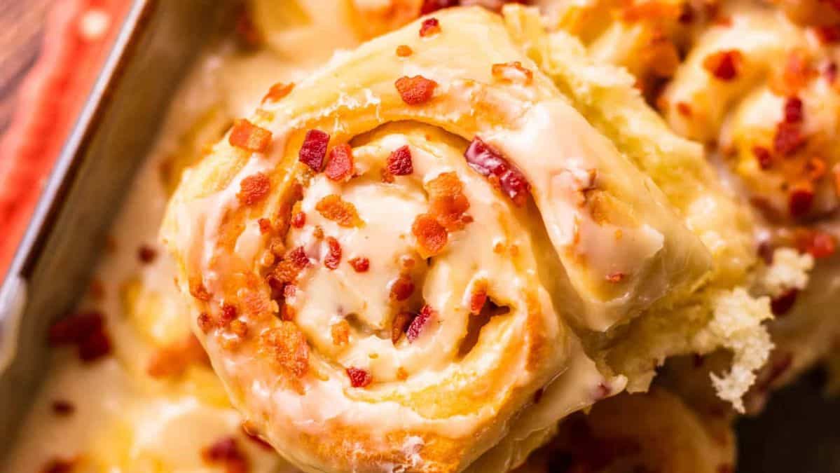 cinnamon rolls topped with icing and crispy bacon bits.