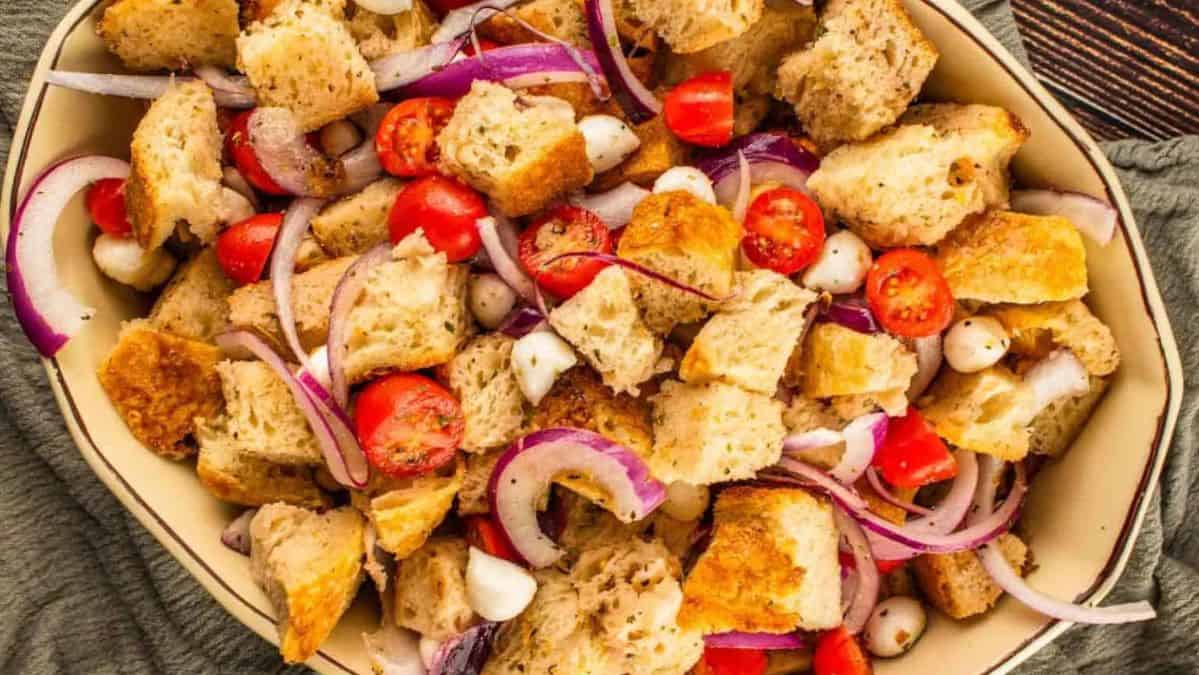 panzanella salad in a dish with tomatoes, red onion and mozzarella balls.