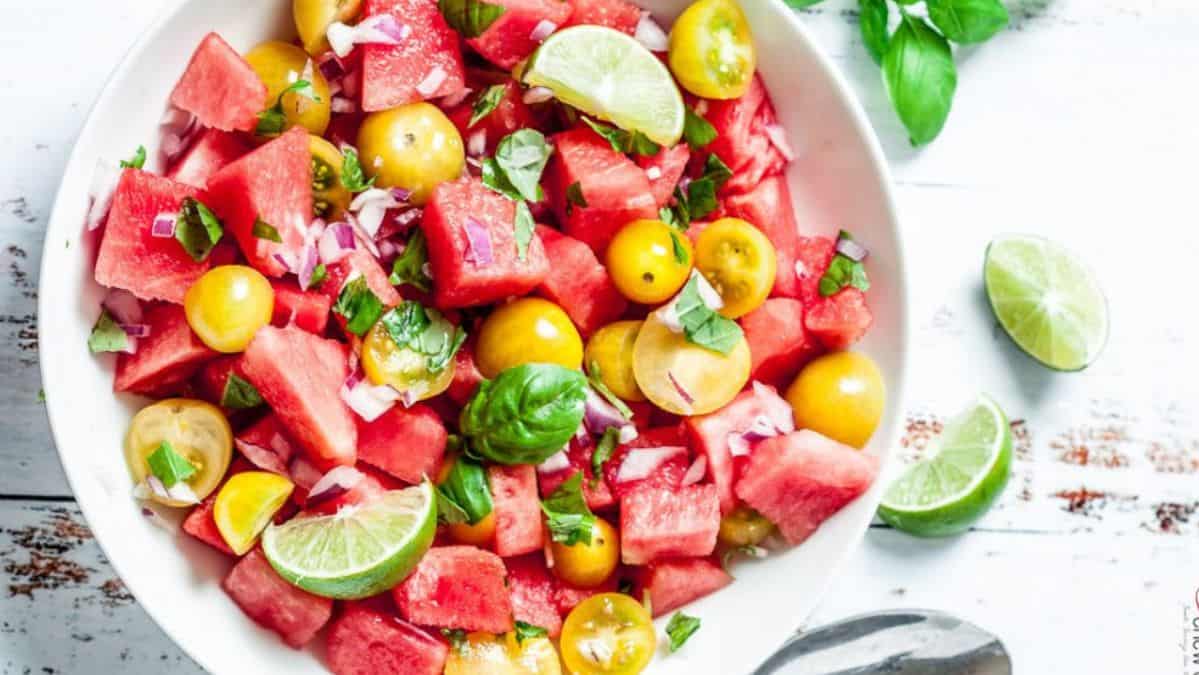 watermelon, tomatoes and fresh herb salad in a white bowl.