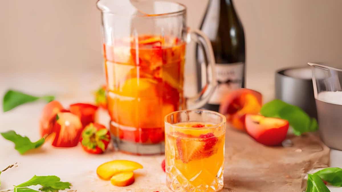 peach, strawberry and raspberry sangria in a pitcher and a glass.