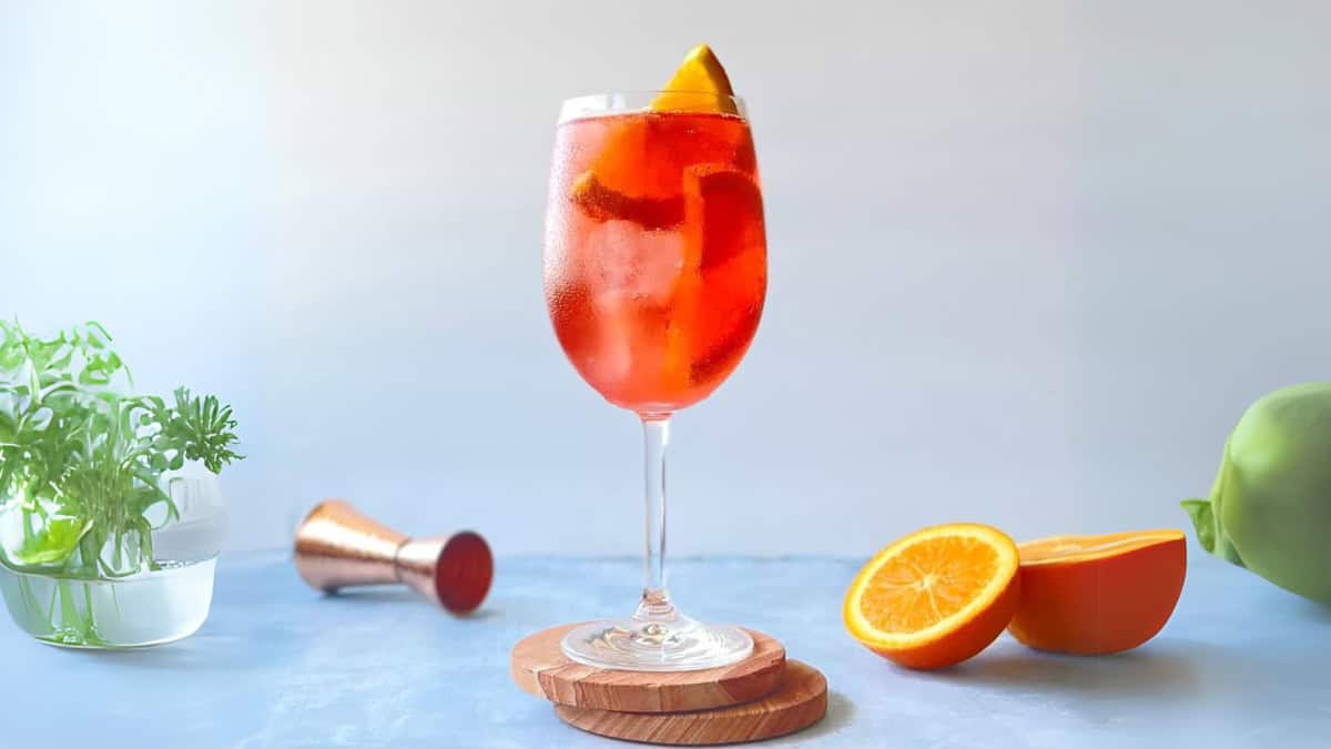 negroni spritz garnished with a fresh orange wedge in a wine glass.