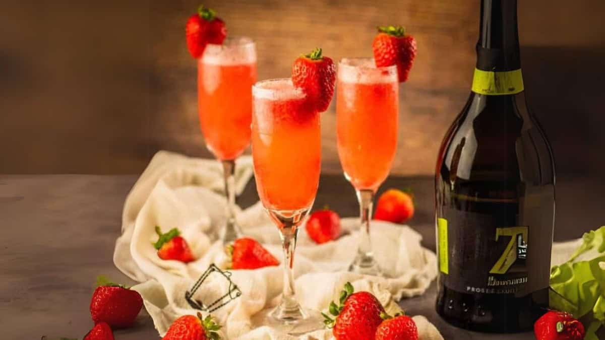 three champagne flutes filled with rossini cocktail garnished with a fresh strawberry.