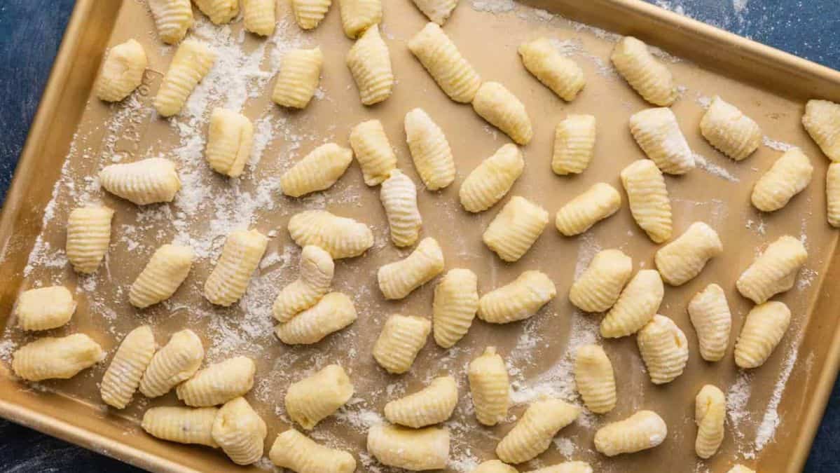 homemade potato gnocchi before cooking on a floured sheet pan.