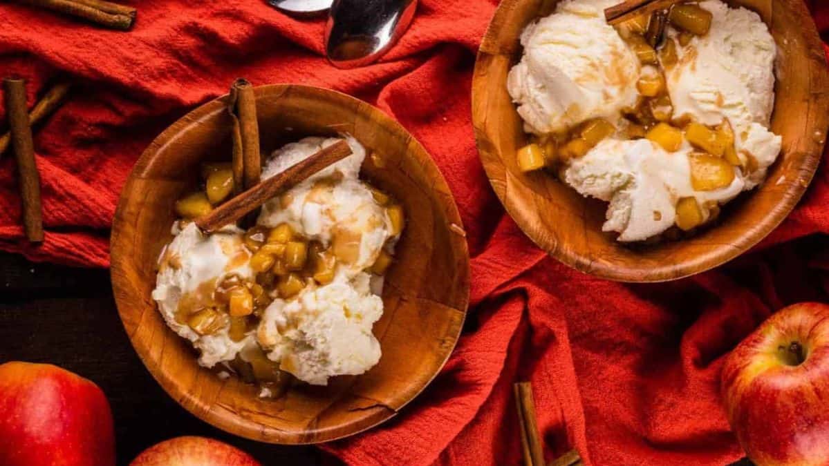 wooden bowls with vanilla ice cream topped with caramel apple topping.