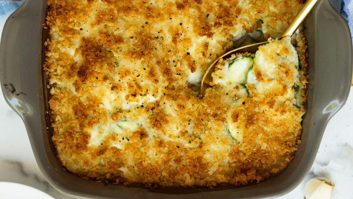 baking dish filled with a casserole with crispy topping with a spoon scooping into it.