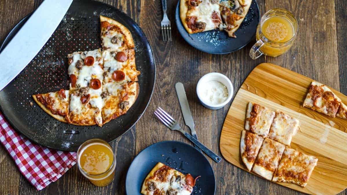 tavern pizzas on a plate and dish with some pieces cut from it.