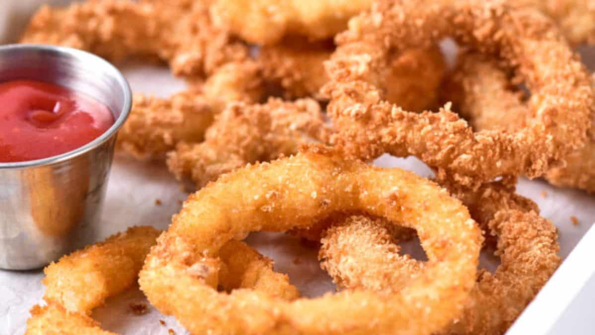 crispy fried onion rings on a platter next to a small dish of ketchup.