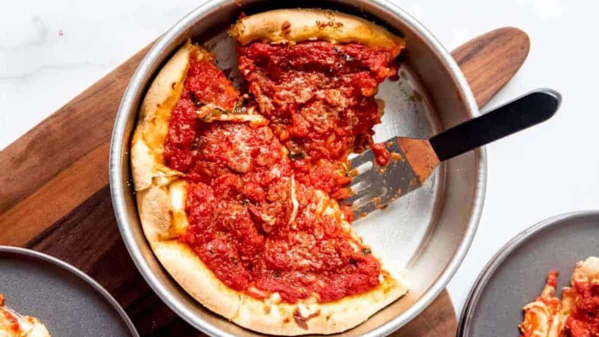 deep dish pizza in a pan with some pieces removed.