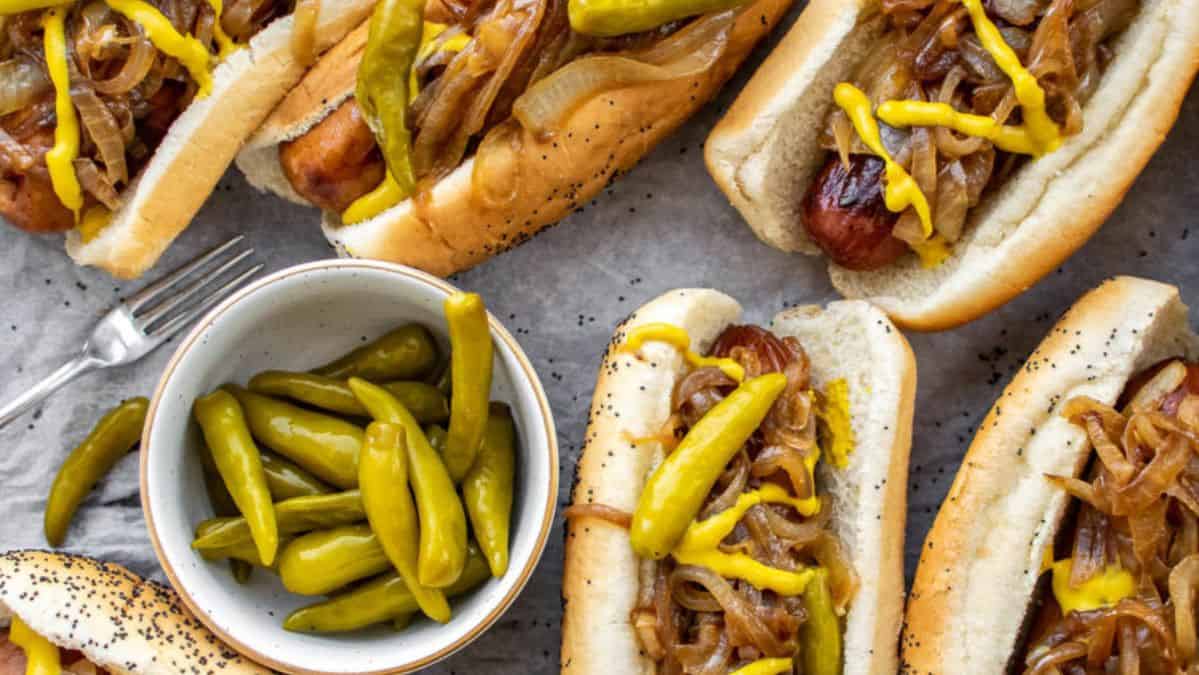 maxwell street polish dogs with a dish of peppers next to them.