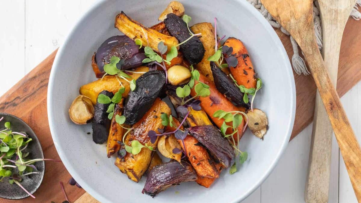 roasted colored carrots in a bowl with fresh herbs.