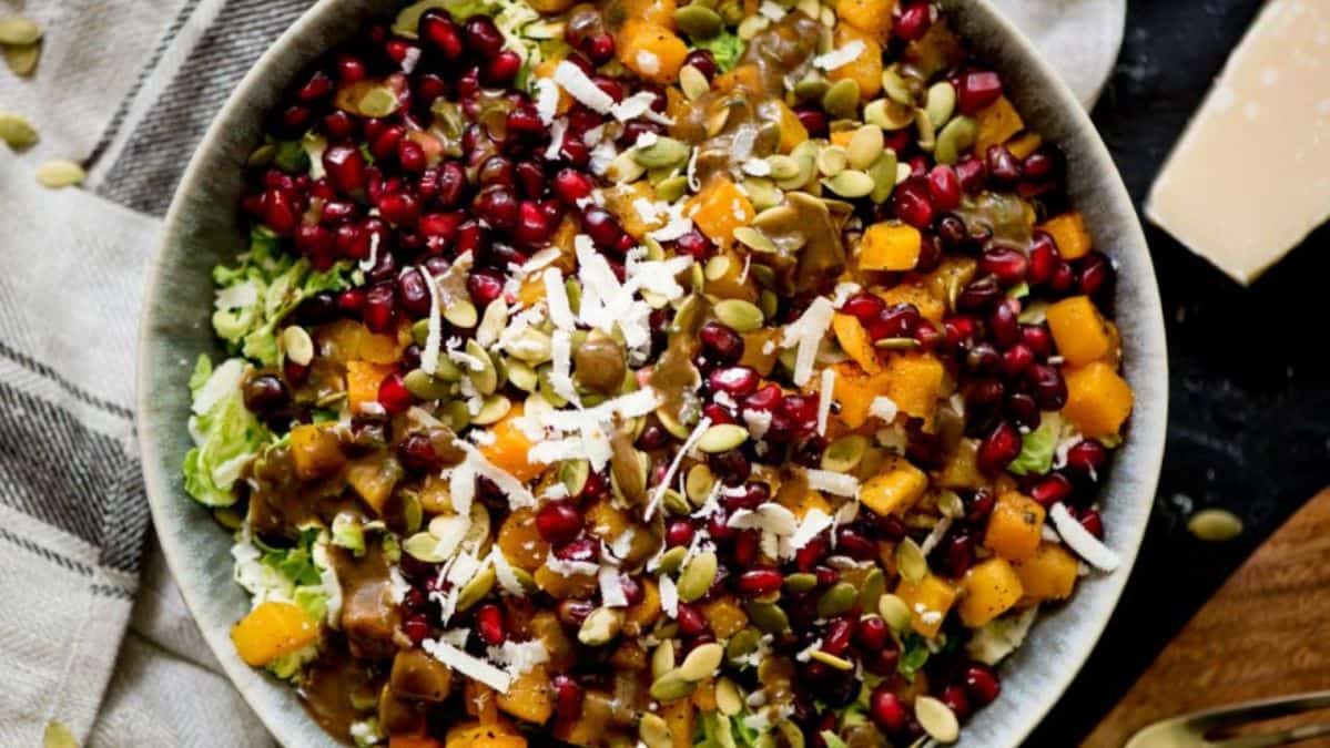 Salad in a bowl with pomegranates vegetables and seeds.