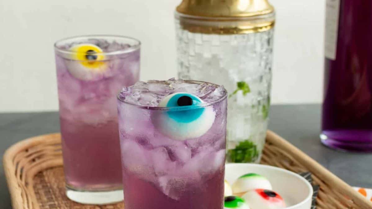 Purple cocktail into glasses with a pretend eyeball floating in it with ice.