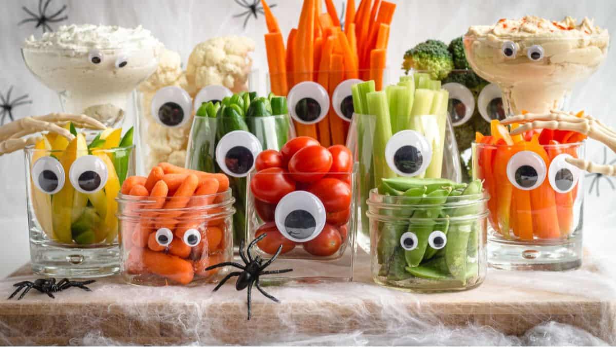 Sliced vegetables in cups with googly eyes on them.