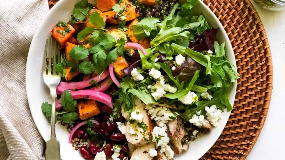 Salad topped with pickled red onions, cheese, and fresh herbs.