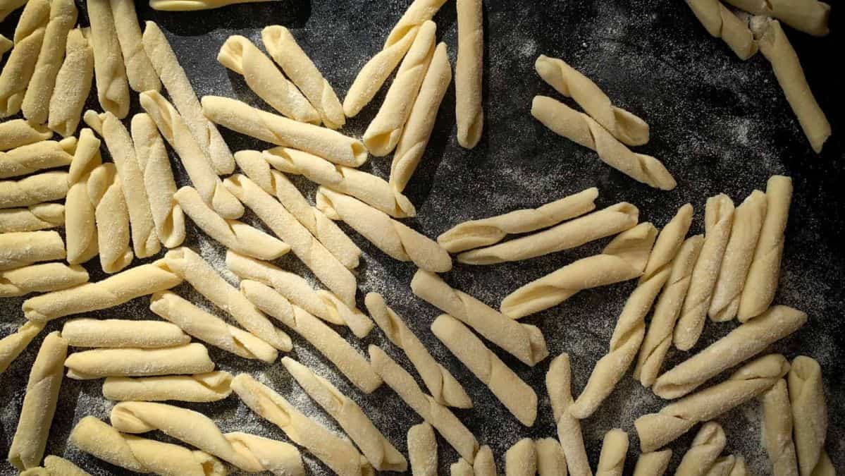 Uncooked fusilli pasta on a table sprinkled with semolina flour.