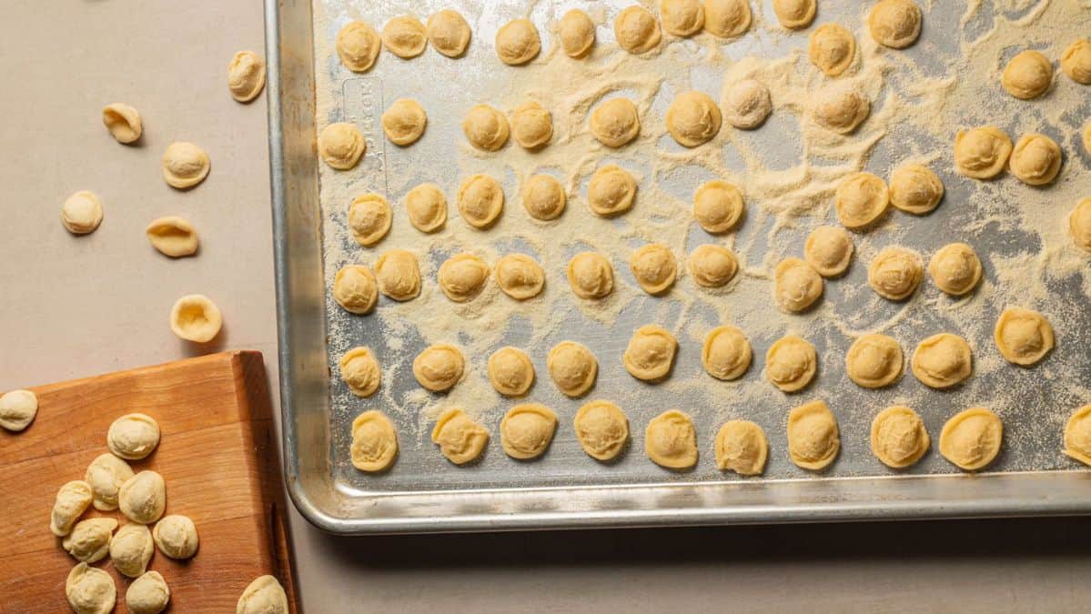 Orecchiette pasta on a sheet pan sprinkled with semolina flour.