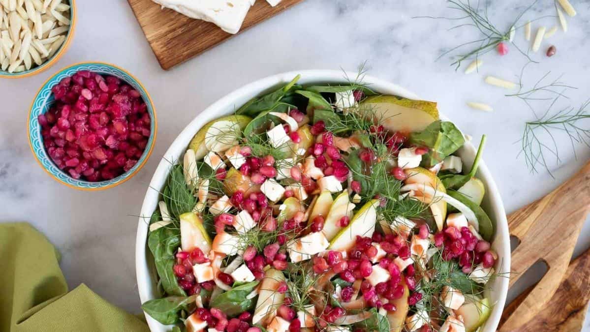 Salad topped with pears and fennel and pomegranate seeds.