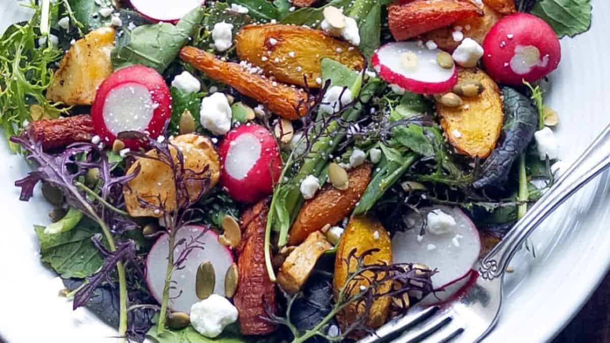 Salad topped with roasted carrots, cheese, and sliced radishes.