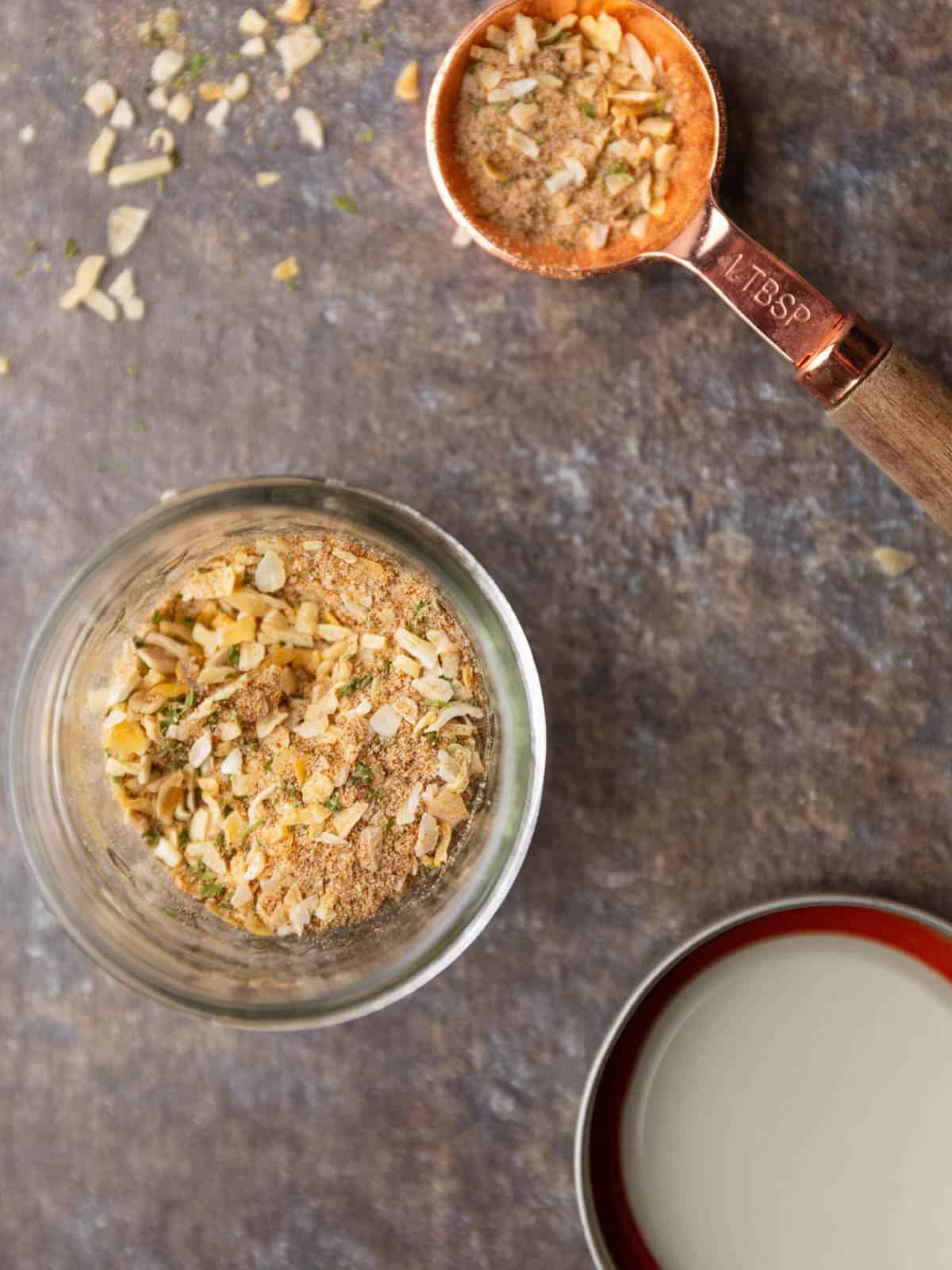 A mason jar and tablespoon with seasoning mix in it.