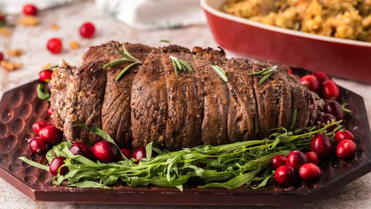 Roasted stuffed flank, steak, garnished with whole cranberries and fresh herbs.