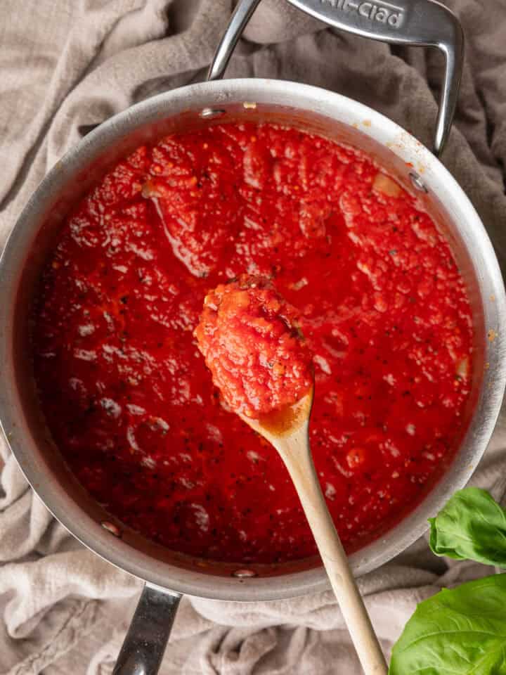 wooden spoon holding a scoop of red sauce over a pot.