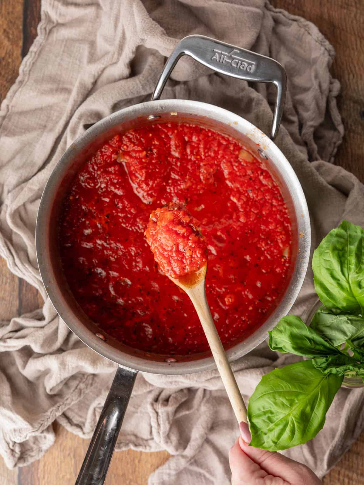 pot of marinara with a wooden spoon holding a scoop over it.