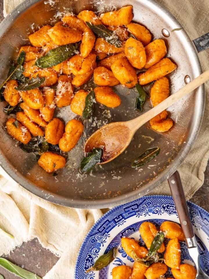 A skillet and bowl with sweet potato gnocchi in it with a sage brown butter sauce.