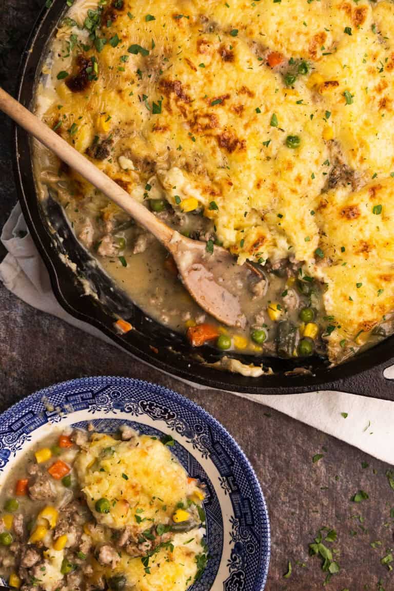 Ground turkey shepherd's pie in a cast iron skillet with a wooden spoon sticking out.