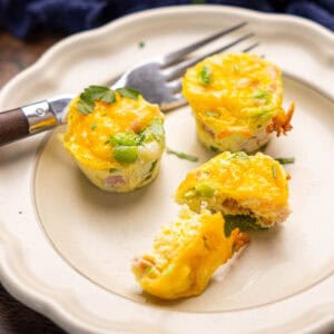 Three baked egg bites on a plate with a fork, one but cut in half.